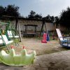 Un parco giochi con altalene, scivoli e un girello colorato.