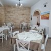 Sala ristorante con pareti in pietra, tavoli apparecchiati e sedie bianche.