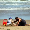Adulto e bambino giocano sulla spiaggia.