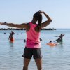Istruttrice di fitness in mare con gruppo di persone.