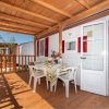 Veranda con tavolo, sedie bianche e arredo variopinto.