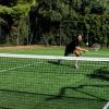 Uomo gioca a tennis su campo in erba.