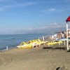 Spiaggia sabbiosa con pedalò gialli e torretta di avvistamento rossa.