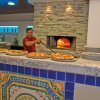Uomo prepara pizze vicino a un forno a legna, su un bancone decorato.