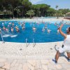 Una piscina con molte persone che fanno acquagym mentre un istruttore le guida dalla riva.