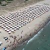 Spiaggia affollata con file di ombrelloni e bagnanti.