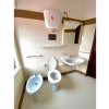 Bagno con bidet, water, lavabo e specchio. Piastrelle beige e cisterna in alto.