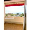 Balcone con vista mare, tettoie rosse e sedile appeso al muro.